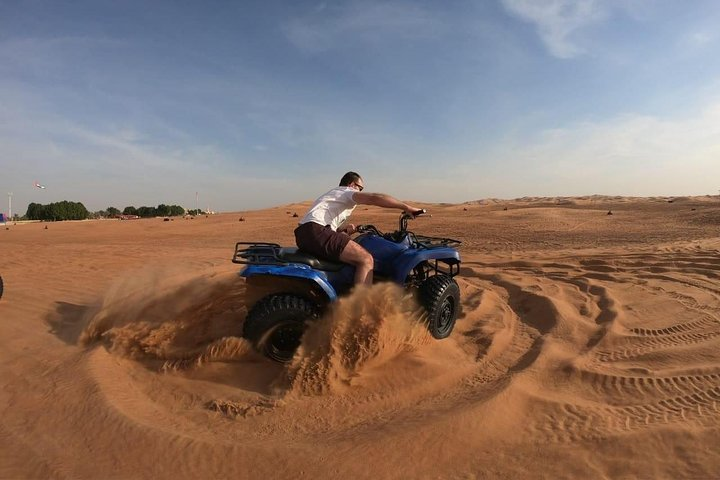 Experience the thrill of riding through the serene Arabian Desert on an ATV leaving tracks in the soft sand while soaking in the stunning natural beauty around you.